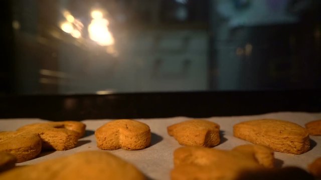 man pulls out ginger biscuits out of the oven