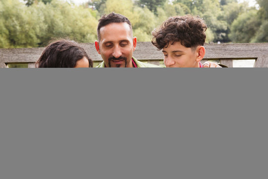 Father sitting on bench with son and daughter, daughter counting on fingers