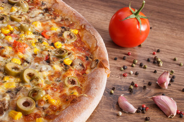 Vegetarian pizza and ingredients with spices on rustic wooden background, fast food