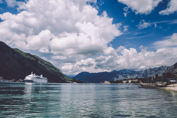 Cruise ship and cloudy sky over Boka Kotorska near Kotor, Montenegro. Kotor bay landscape with mountains and clouds.