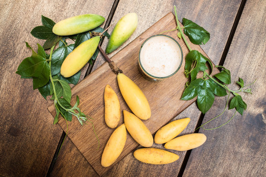 Vaso de Jugo y Curubas - Frutas ex&oacute;ticas del tr&oacute;pico sobre fondo de madera natural - toma de estudio desde arriba - luz natural