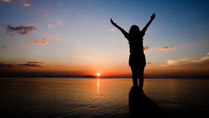Photo of beautiful sunset on the beach and woman silhouette. Colorful sky.