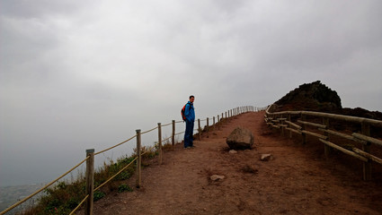 A young man stands on the deserted road. The view from afar