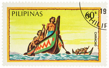 Group of the natives in traditional boat on postage stamp