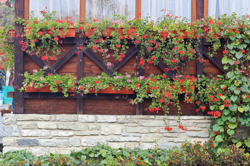 Fototapeta na wymiar Balcony from wooden and stones with red flowers