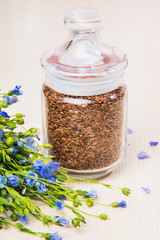 Obraz na płótnie Canvas Linseed oil, flax seeds, and flowers on a light background.