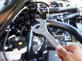 Hand with wrench checking car engine.