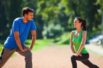 Young couple stretching their bodies, warming up for jogging. 