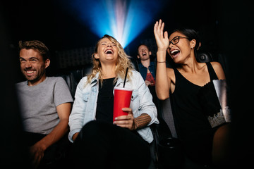 Young friends watching comedy movie on theater - obrazy, fototapety, plakaty