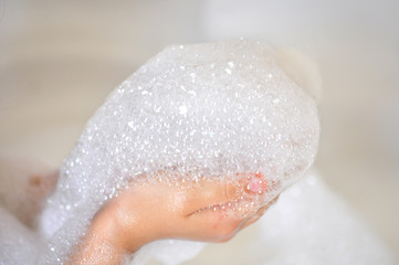 hands in a bath with foam of soap