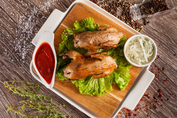 Quails grilled on a wooden board and a white plate, spilling aro