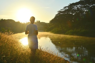 Girl in clumps of grass / Girl in clumps of grass in the morning light and water during the morning on the river.