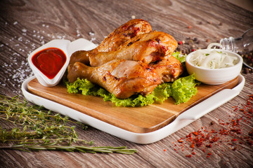 Chicken legs grilled on a wooden board with white cup and around