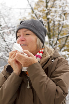 senior woman sneezing outdoors winter
