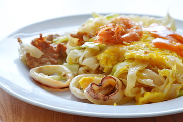 stir fried rice noodle seafood and egg with cabbage dressing chili on dish