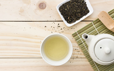 cup with green tea and teapot on wooden table background. over light
