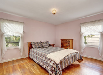 Bedroom interior with hardwood floor and soft pink walls