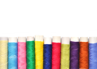 Pile of coloured bobbins of lurex thread isolated on white