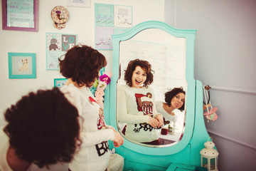 beautiful and funny twins in cute sweaters look in the mirror
