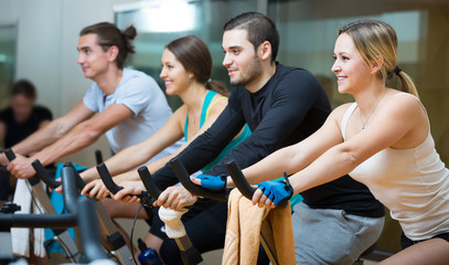 Young adults on exercise bikes in gym