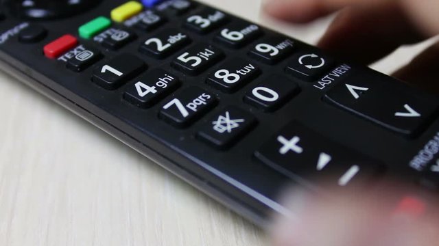 human hand changes the channels on the TV remote control
