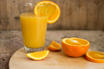 Fresh orange juice with slice of orange on wooden table