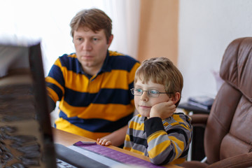 father and little kid boy learning and making school homework on computer