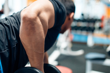 Fototapeta na wymiar Bodybuilder with dumbbell flexing muscles in gym