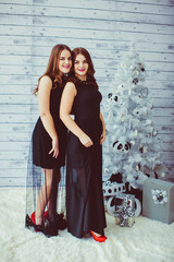 happy and beautiful sisters in black dresses standing near the C