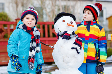 Two little siblings boys making a snowman