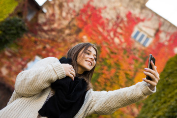 Smile girl take selfie on yellow and red leaves background