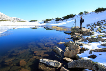 Fototapeta premium Photographer taking photos of beautiful landscape in the mountain lake. Winter lake. Travel inspiration and motivation, beautiful landscape.