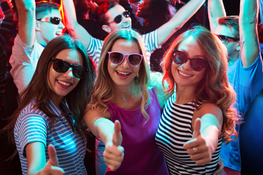 Group of girls dancing near the friends and showing OK sign