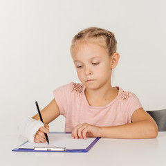 little girl with broken arm is sitting at the table