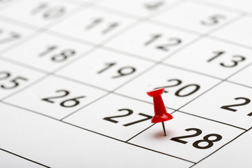 Pin on the date number 28. The twenty-eighth day of the month is marked with a red thumbtack. Focus point on the red pin.