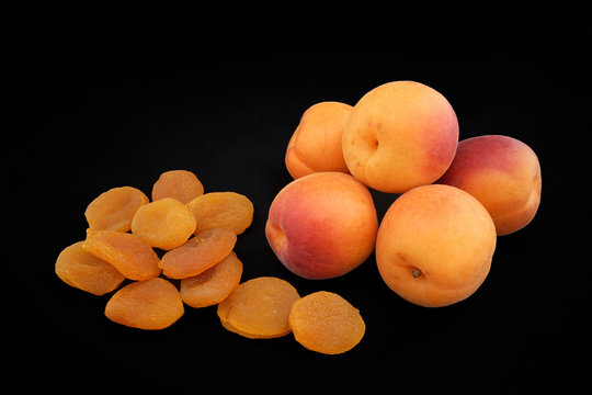 Apricots of yellow color and dried apricots on a black backgroun