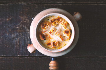Onion soup in the ceramic pot   on the wooden table top view