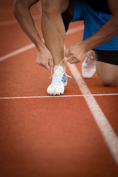 Young Man Runner tying his shoes on a running track. Shoelaces, Urban jogger