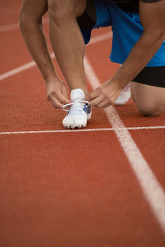 Young Man Runner tying his shoes on a running track. Shoelaces, Urban jogger