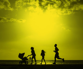 Fototapeta na wymiar Silhouette of family jogging with mother pushing baby cart with color filter effected