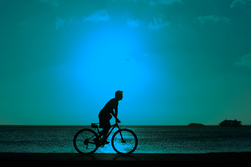Fototapeta premium man ride bicycles outdoors against sunset. Silhouette. with color filter effected
