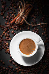 Fresh tasty espresso cup of hot coffee with coffee beans on dark
