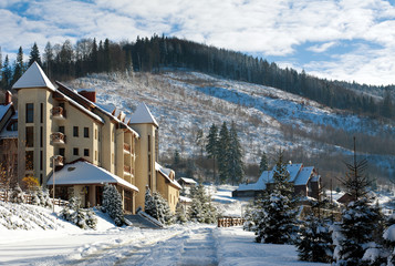 Fototapeta na wymiar Winter snowy village on landscape background of pine forest