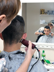 Barber shop that performs the haircut of a young boy with electric clippers.
