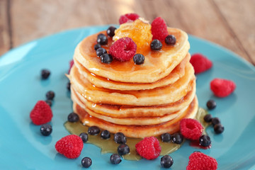 Plate full of tasty pancakes with berries and honey