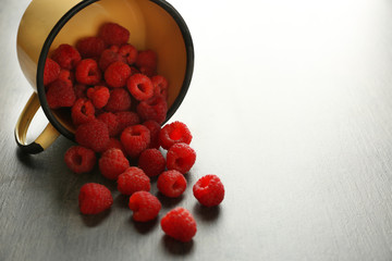 Fresh raspberries in cup on table