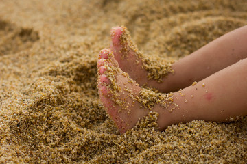 Little girl feet on the sandy beach