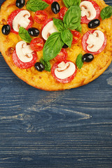 Delicious pizza with mushrooms, cherry tomatoes, olives and basil on blue wooden background