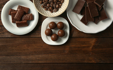 Many plates with chocolate on wooden background, top view