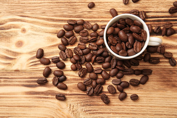 White cup with coffee beans on wooden background